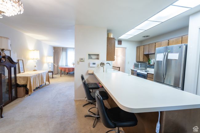 Kitchen featuring freestanding refrigerator, light countertops, white range with electric stovetop, and light carpet | Image 12