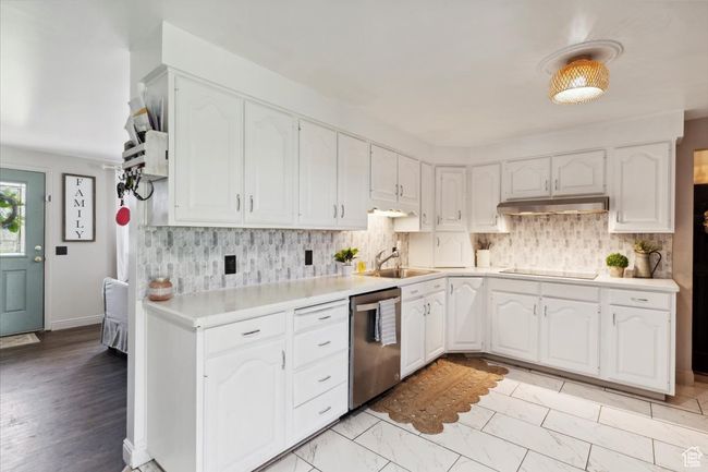 Kitchen with dishwasher, black electric stovetop, white cabinets, and under cabinet range hood | Image 9