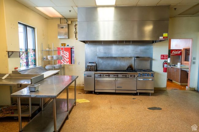 Kitchen with range with two ovens, a drop ceiling, and wall chimney exhaust hood | Image 24