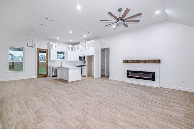Kitchen with open floor plan, stainless steel appliances, light countertops, backsplash, and white cabinetry | Image 5