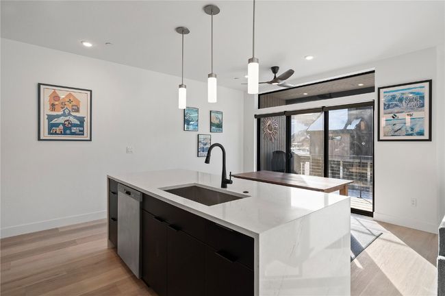 Kitchen featuring light wood-type flooring, sink, decorative light fixtures, dishwasher, and an island with sink | Image 7