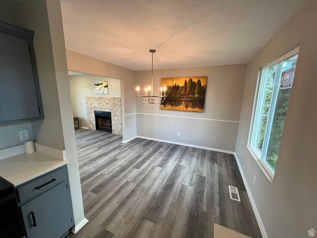 Unfurnished dining area with dark wood finished floors, visible vents, an inviting chandelier, and plenty of natural light | Image 6