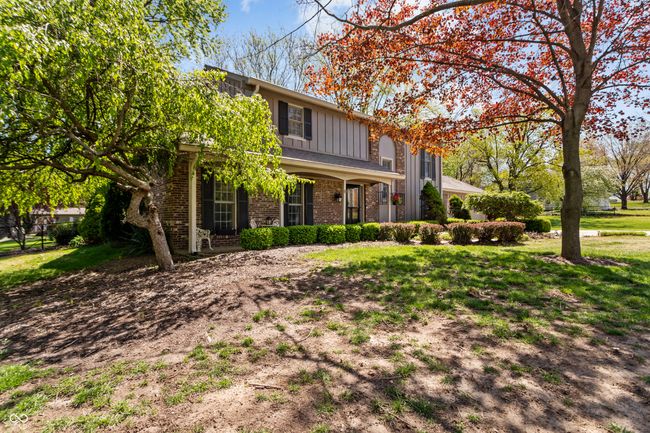 view of front of home featuring board and batten siding, brick siding, a porch, and a front yard | Image 43