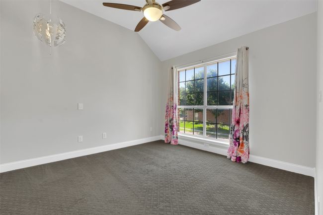 Spare room featuring lofted ceiling, a ceiling fan, and dark carpet | Image 23