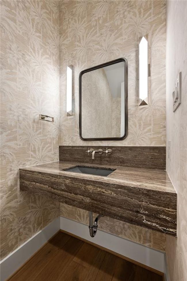 Sophisticated power room featuring a dark stone countertop and modern wall sconces. | Image 7