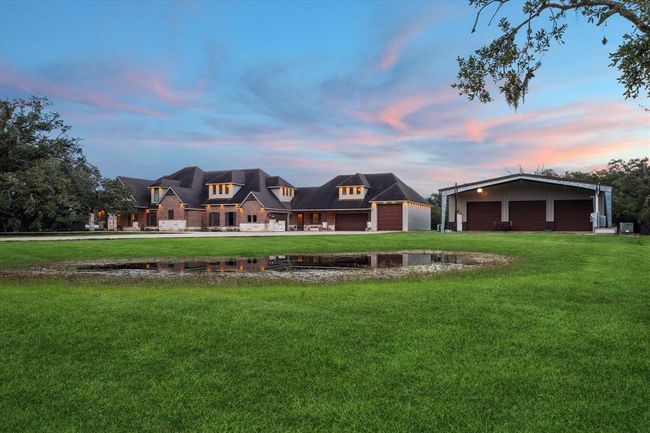A concrete circle driveway gracefully leads to both the main front door and the in-law suite's front entrance, offering convenient access to the two-car garage, three-car garage, boat/RV garage, and shop. With ample parking space, this layout ensures plenty of room for vehicles, boats, RVs, or any other needs, making it ideal for both daily living and entertaining. | Image 49