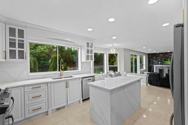 Kitchen featuring a center island, white cabinets, a sink, a healthy amount of sunlight, and stainless steel appliances | Image 8