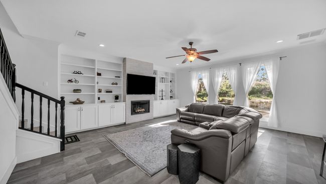 Living room featuring a ceiling fan, recessed lighting, stairway, a large fireplace, and built in features | Image 16