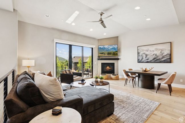 Living room featuring a glass covered fireplace, ceiling fan, wood finished floors, recessed lighting, and lofted ceiling | Image 11