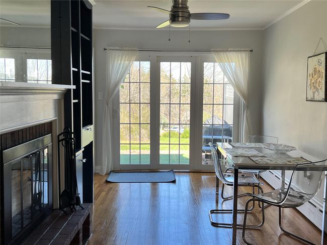 Dining space with wood finished floors, a fireplace with raised hearth, and crown molding | Image 42