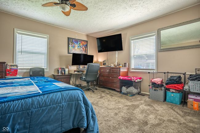 carpeted bedroom with a ceiling fan and a textured ceiling | Image 15
