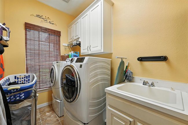 Laundry area featuring washer and dryer, cabinet space, and light tile patterned flooring | Image 9
