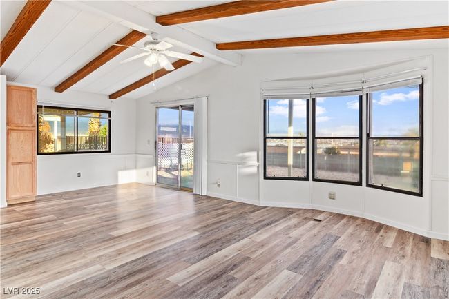 Living room with vaulted ceiling with beams, ceiling fan, and light wood-style flooring | Image 7