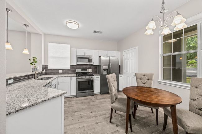 Kitchen with tasteful backsplash, light wood-style flooring, a sink, appliances with stainless steel finishes, and light stone countertops | Image 15