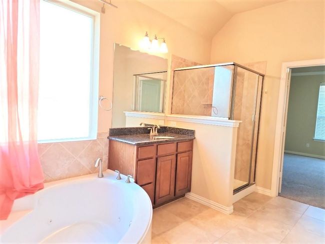 Bathroom with a tub with jets, vanity, a shower stall, tile patterned floors, and lofted ceiling | Image 19