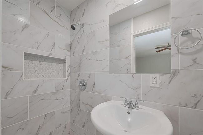 The private en suite features a shower area and gray-and-white tiled finishes that echo the home’s cohesive design. | Image 18