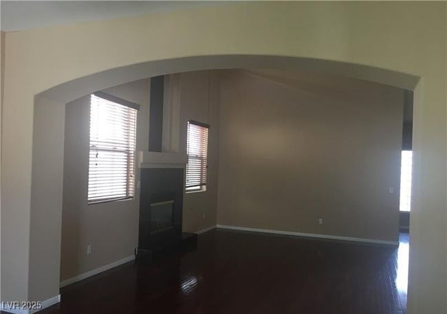 Unfurnished living room featuring healthy amount of natural light, dark wood finished floors, arched walkways, and a glass covered fireplace | Image 4