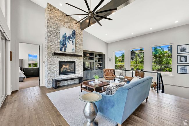 Living area featuring high vaulted ceiling, a fireplace, hardwood / wood-style flooring, and recessed lighting | Image 15