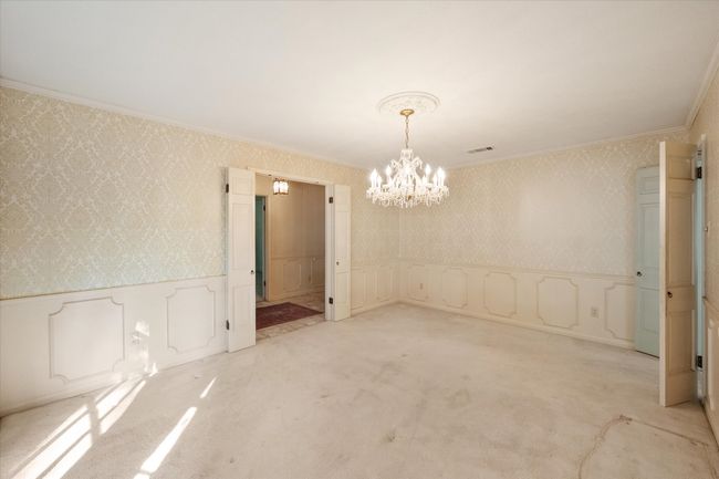 Wool carpeted dining room with crystal chandelier, wallpapered walls, wainscoting, and gorgeous wood bay window | Image 20