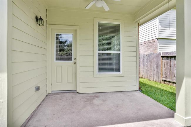 Step outside to the backyard and enjoy a covered patio with a ceiling fan, providing a comfortable space to relax or entertain while overlooking the spacious yard. | Image 23