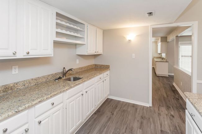 Wet bar, white cabinetry, dark wood-type flooring, and open shelves | Image 12
