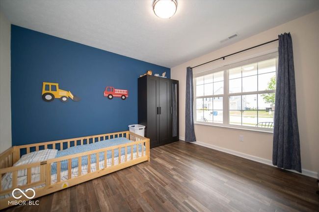 bedroom featuring dark vinyl flooring with wood appearance and baseboards. French doors and a closet were added to make this versatile room into a 4th bedroom. It can easily be used as an office, dining room, or playroom. | Image 11
