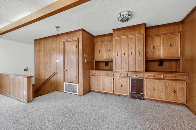 Unfurnished living room featuring wooden walls, light carpet, a textured ceiling, and baseboards | Image 29