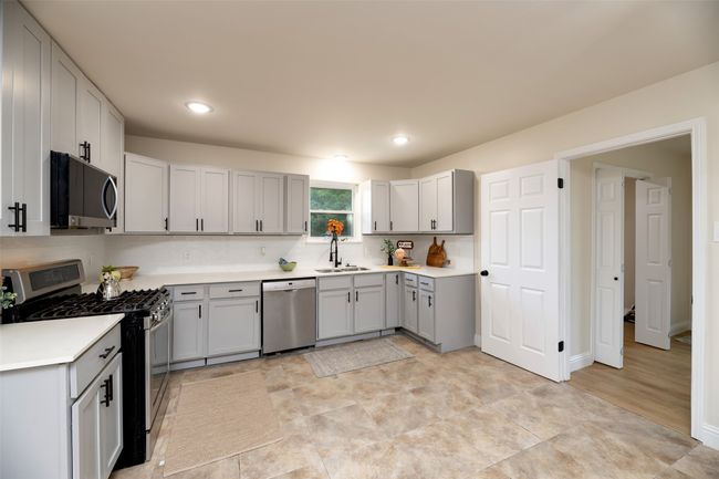 Kitchen featuring stainless steel appliances, gray cabinetry, light countertops, a sink, and recessed lighting | Image 8