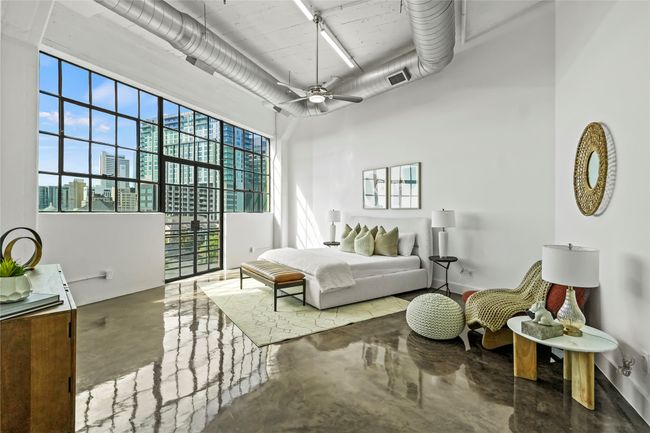Bedroom featuring ceiling fan, visible vents, a city view, a towering ceiling, and finished concrete flooring | Image 23