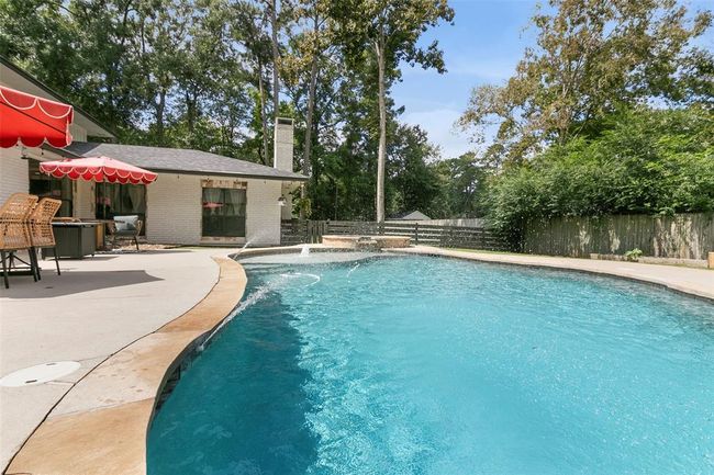 This photo showcases a spacious backyard with a large, inviting swimming pool surrounded by a well-maintained patio area. The setting is enhanced by outdoor seating, a barbecue area, and lush greenery, offering a perfect space for relaxation and entertainment. | Image 44