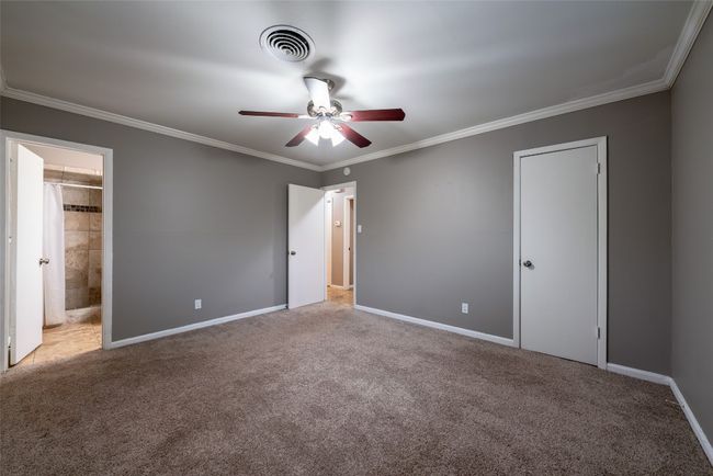 Unfurnished bedroom featuring carpet floors, crown molding, connected bathroom, and a ceiling fan | Image 21