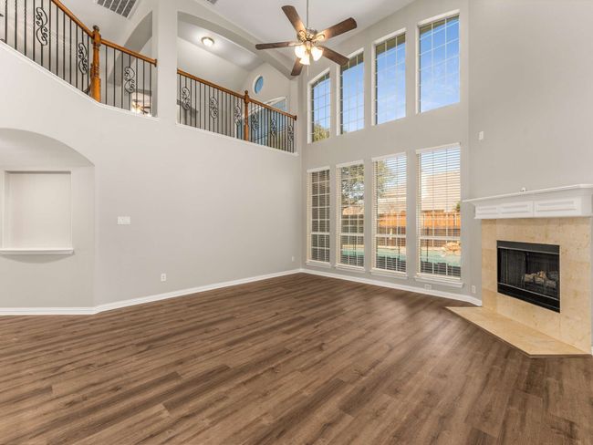 Unfurnished living room with visible vents, a ceiling fan, wood finished floors, baseboards, and a tile fireplace | Image 10