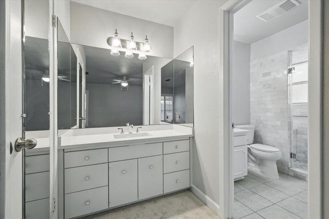 Bathroom with a stall shower, toilet, visible vents, ceiling fan, and vanity | Image 23