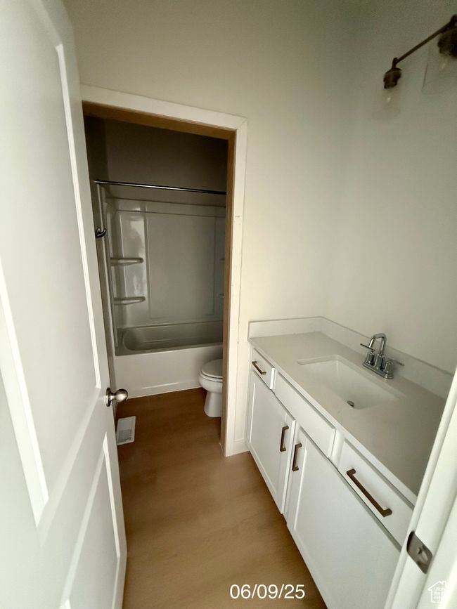 Bathroom featuring vanity, wood finished floors, toilet, and shower / bathtub combination | Image 12