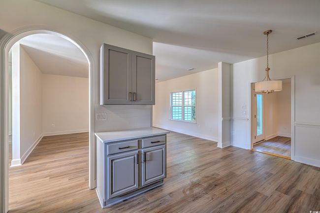 Kitchen featuring gray cabinetry, light wood-style flooring, light countertops, and arched walkways | Image 24