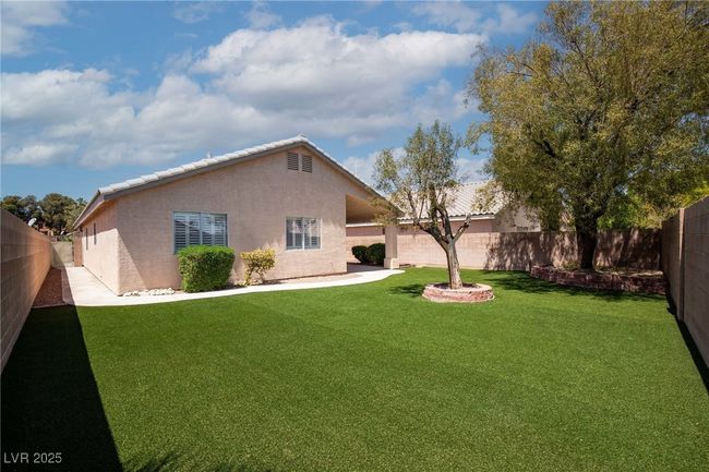 Rear view of house featuring a fenced backyard, stucco siding, and a lawn | Image 33