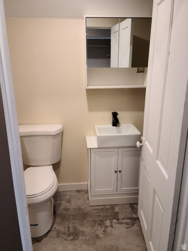 Bathroom with vanity, toilet, baseboards, and concrete flooring | Image 24