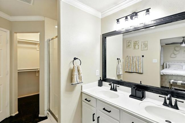 The primary ensuite includes a dual-sink vanity with framed mirror, modern fixtures, a glass-enclosed shower, and a generous walk-in closet. | Image 16