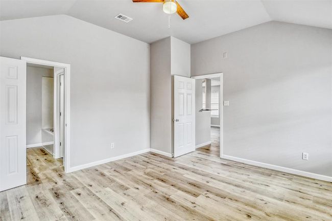 Welcome to your private retreat! The primary bedroom, located just off the living area, features durable vinyl flooring, soft decorator paint, and a soaring ceiling with an updated ceiling fan for added comfort and style. | Image 18