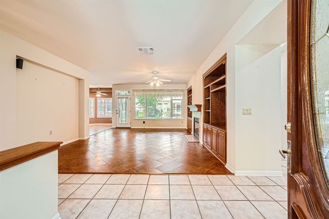 Unfurnished living room featuring a ceiling fan, a glass covered fireplace, and baseboards | Image 23
