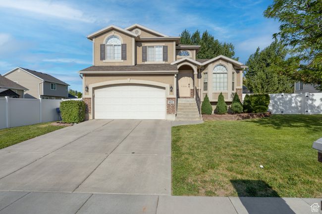 View of front of property featuring stucco siding, a garage, concrete driveway, and brick siding | Image 30