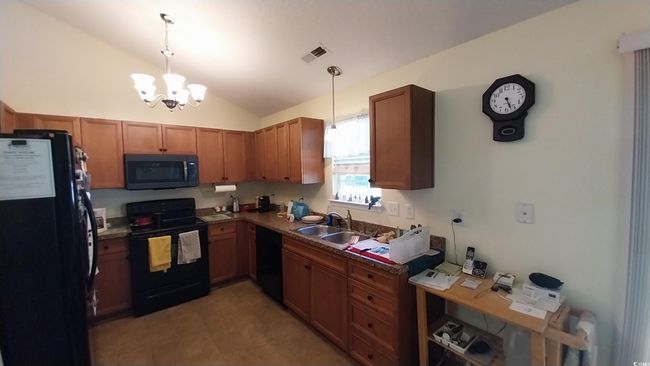 Kitchen featuring black appliances, lofted ceiling, a chandelier, decorative light fixtures, and brown cabinets | Image 5