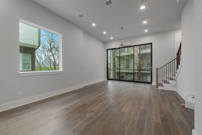 Unfurnished living room with baseboards, wood finished floors, visible vents, and stairs | Image 11