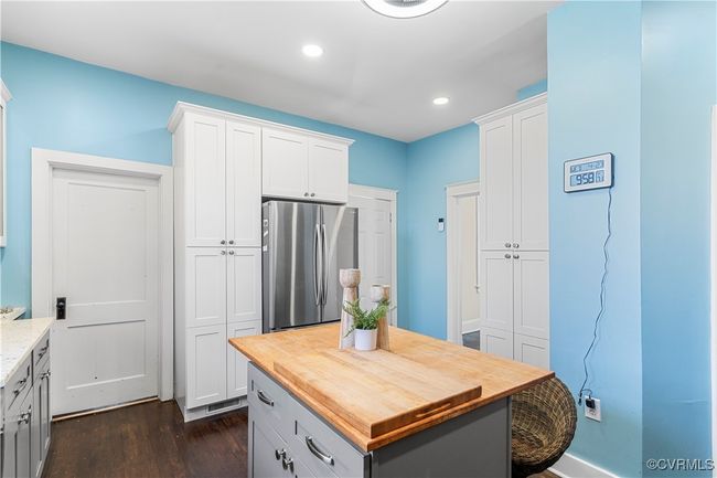 Kitchen with dark wood-style flooring, freestanding refrigerator, recessed lighting, white cabinetry, and butcher block counters | Image 15
