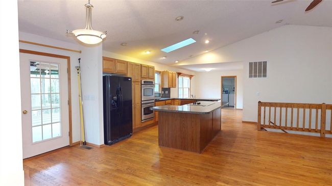 Kitchen with dark countertops, visible vents, stainless steel double oven, a peninsula, and black fridge with ice dispenser | Image 11