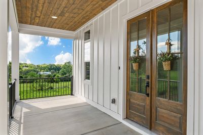 The view of the front covered porch accenting the iron hand rails and 8 foot tall wooden double doors. Bring your comfy chairs or porch swing and enjoy the serene views that this porch has to offer. | Image 2