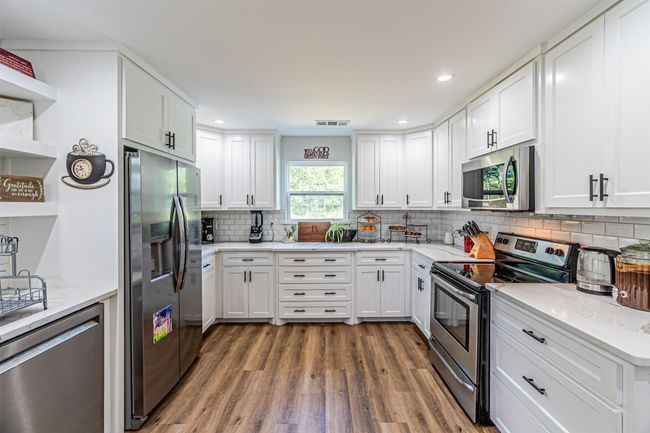 Kitchen with stainless steel appliances, open shelves, wood finished floors, white cabinets, and recessed lighting | Image 13