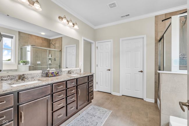 master bath w/tiled shower stall, double sinks, ornamental molding, and tile flooring | Image 36