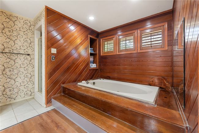 Bathroom with crown molding, a bath, a shower with door, wallpapered walls, and baseboards | Image 29