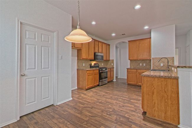 Kitchen with gas stove, arched walkways, dark wood-style flooring, tasteful backsplash, and recessed lighting | Image 11